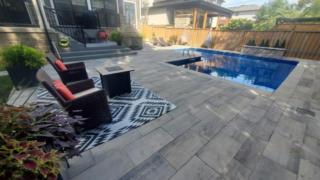 Modern Backyard Retreat with Interlock on Pool Deck and Walkway